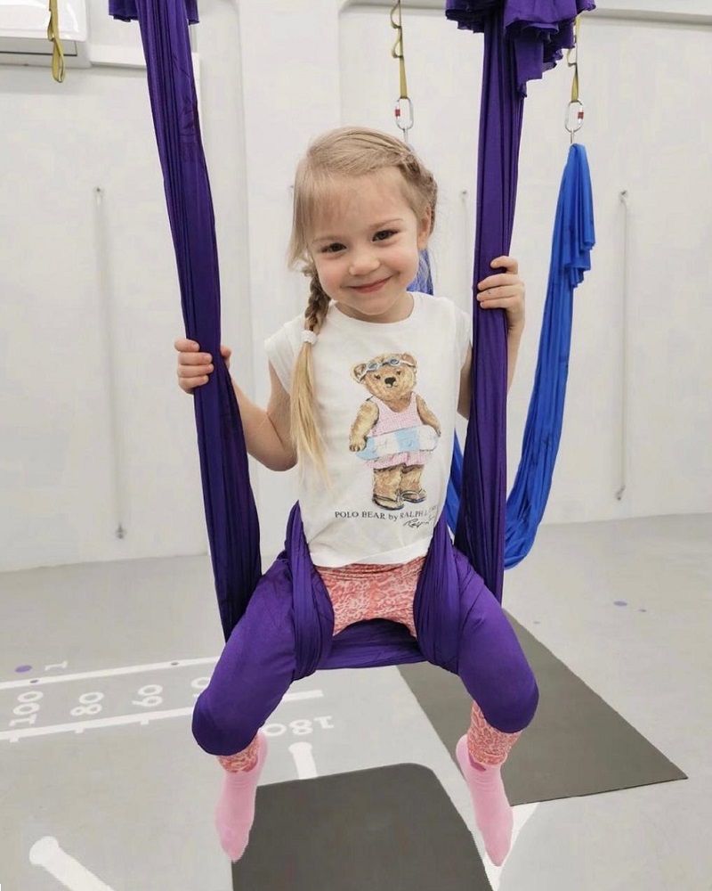 Девочка сидит в фиолетовом гамаке на занятии AntiGravity kids